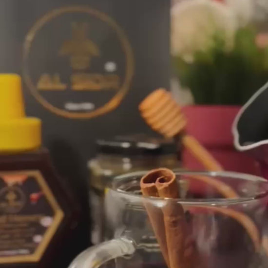 A glass cup with a cinnamon stick, honey jar, and elegant packaging, showcasing pure organic honey in Abu Dhabi.
