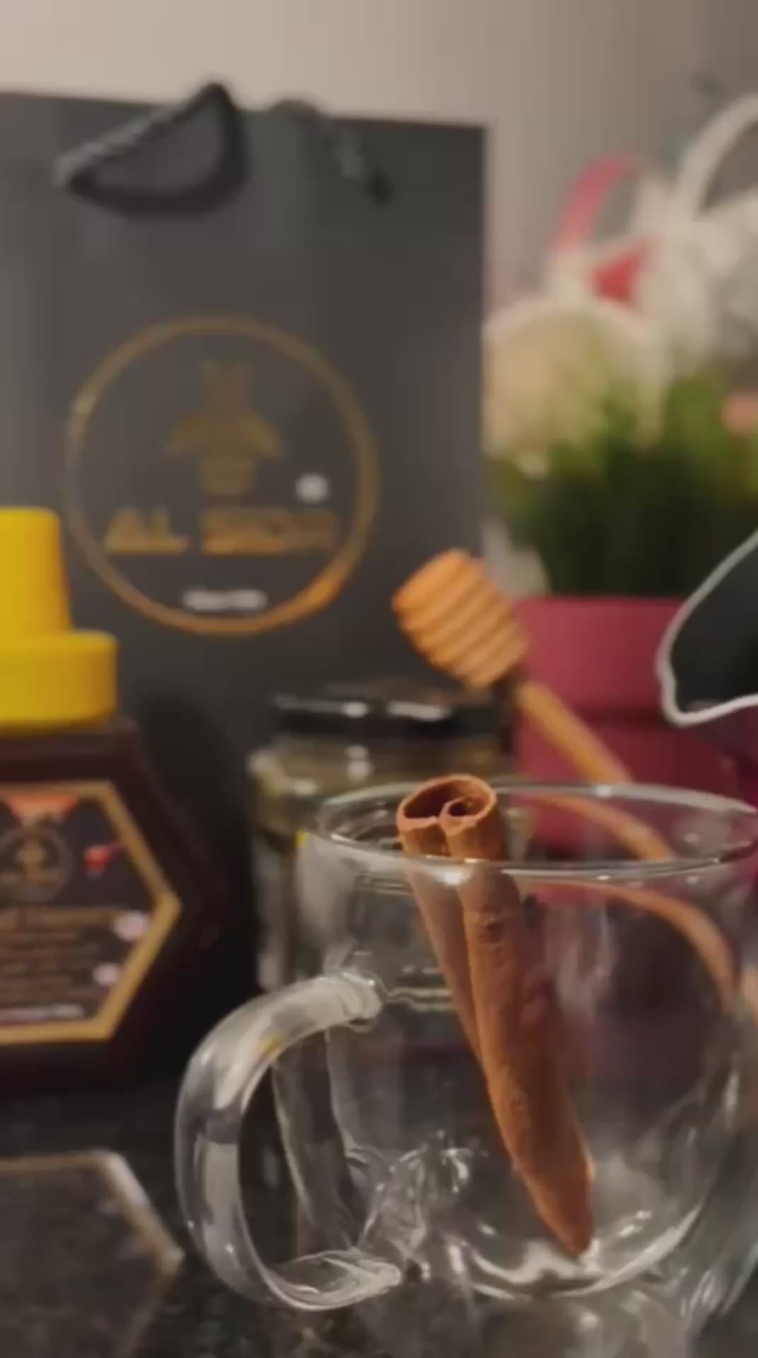 A glass cup with a cinnamon stick, honey jar, and elegant packaging, showcasing pure organic honey in Abu Dhabi.